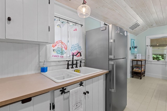 1205 Massasoit Rd, Eastham, MA 02642 - kitchen with freestanding refrigerator, white cabinetry, light countertops, lofted ceiling, and hanging light fixtures