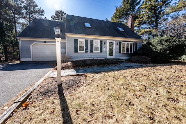 cape cod home featuring a garage, driveway, and a chimney