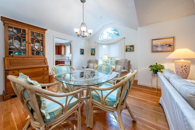 dining room with vaulted ceiling, an inviting chandelier, and light hardwood / wood-style floors