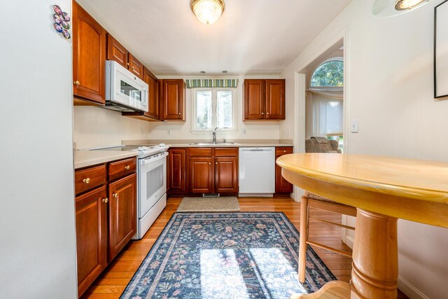 kitchen featuring sink, white appliances, and light hardwood / wood-style flooring