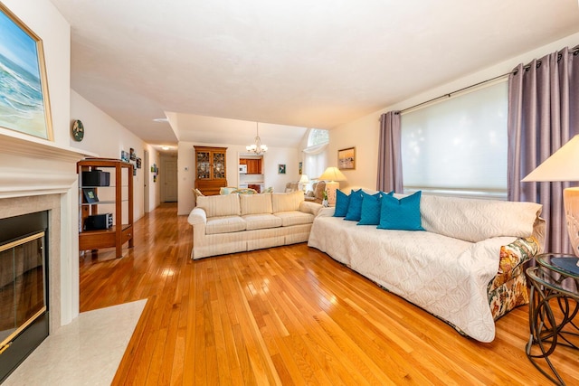 living room with hardwood / wood-style flooring, a notable chandelier, and vaulted ceiling