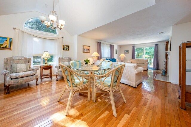 dining room featuring light hardwood / wood-style flooring, lofted ceiling, and an inviting chandelier