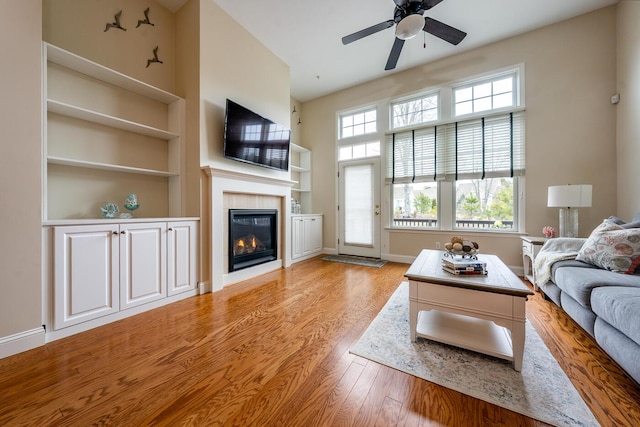 45 Grey Hawk Dr Unit 578, Mashpee, MA 02649 - unfurnished living room with a tiled fireplace, a ceiling fan, light wood finished floors, built in features, and baseboards