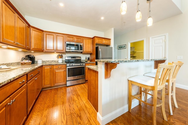 45 Grey Hawk Dr Unit 578, Mashpee, MA 02649 - kitchen featuring light wood-style flooring, brown cabinets, a kitchen breakfast bar, and appliances with stainless steel finishes