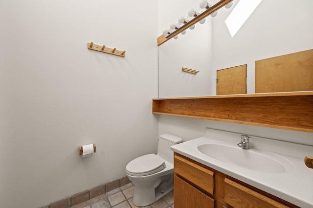 half bath with toilet, vanity, and a skylight