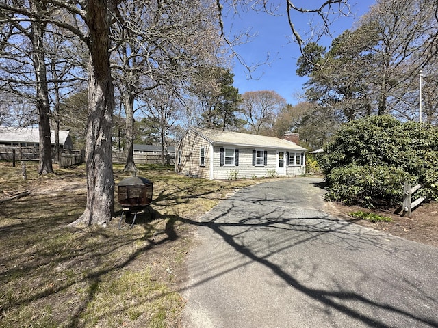 view of front of property featuring aphalt driveway, fence, and a chimney