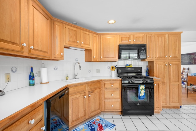 kitchen featuring light countertops, light tile patterned floors, a sink, black appliances, and tasteful backsplash