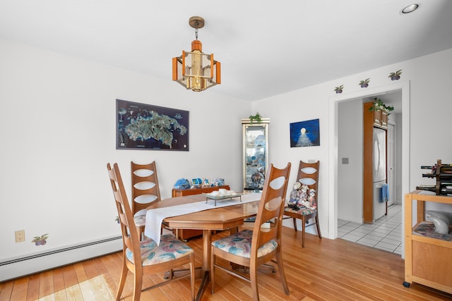 dining room featuring a baseboard heating unit, light wood finished floors, and a notable chandelier
