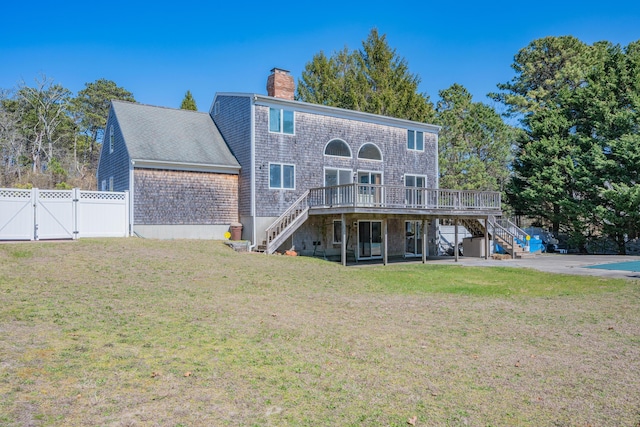rear view of property featuring stairway, a wooden deck, fence, and a gate