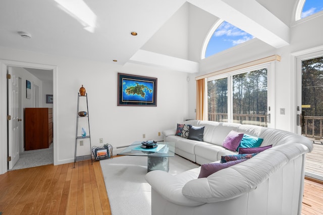 living area with a baseboard heating unit, a towering ceiling, and light wood-style floors