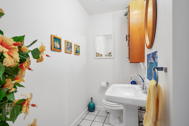 half bathroom with tile patterned flooring, baseboards, and toilet