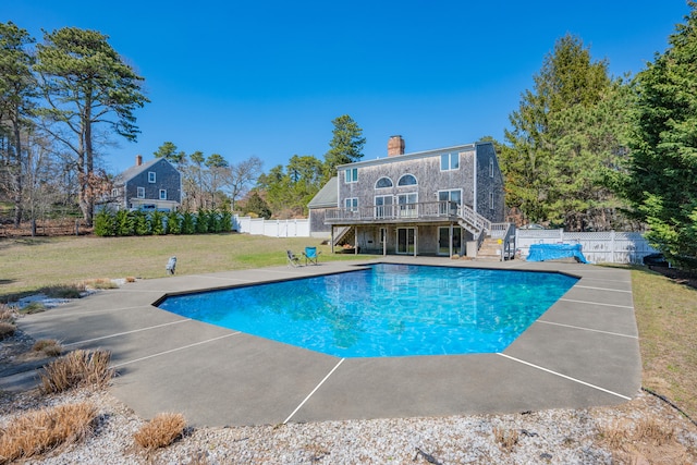 view of swimming pool with a fenced backyard, a wooden deck, stairway, and a yard