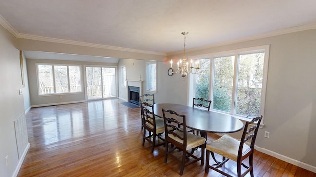 23 W Woods Vlg, Yarmouth Port, MA 02675 - dining area with healthy amount of natural light, wood finished floors, a fireplace with flush hearth, ornamental molding, and a chandelier