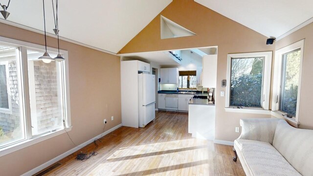 23 W Woods Vlg, Yarmouth Port, MA 02675 - kitchen featuring white appliances, light wood-type flooring, white cabinets, high vaulted ceiling, and pendant lighting
