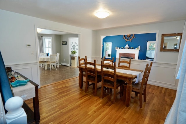 57 Camden Ln, Mashpee, MA 02649 - dining space with a baseboard heating unit, light wood-style flooring, wainscoting, and a fireplace