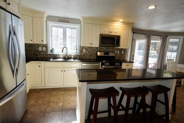 57 Camden Ln, Mashpee, MA 02649 - kitchen featuring stainless steel appliances, a sink, dark countertops, tasteful backsplash, and a breakfast bar