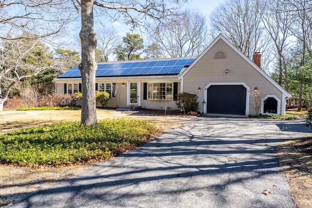 view of front of house with metal roof, a garage, solar panels, and driveway