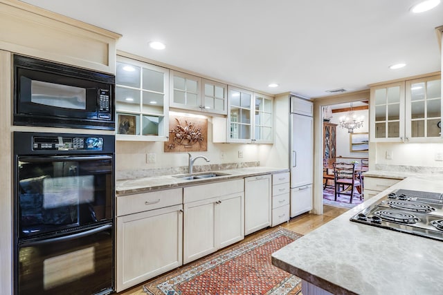 kitchen with a sink, black appliances, a chandelier, glass insert cabinets, and recessed lighting