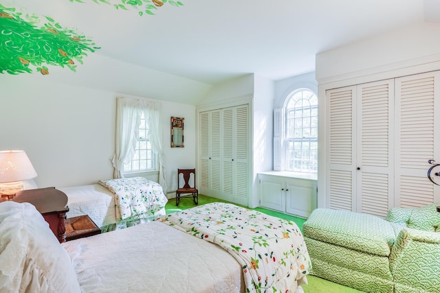carpeted bedroom with multiple closets and vaulted ceiling