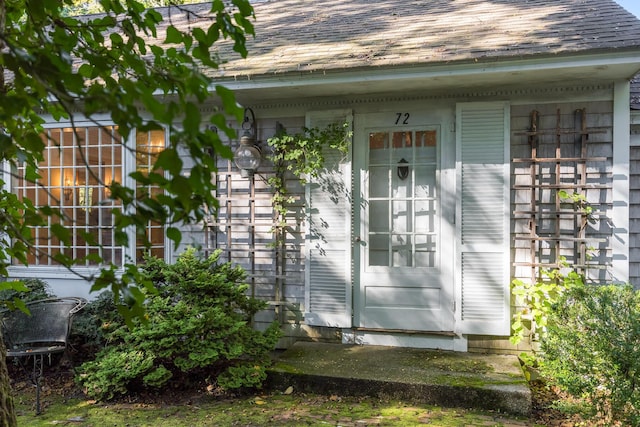 view of exterior entry featuring a shingled roof