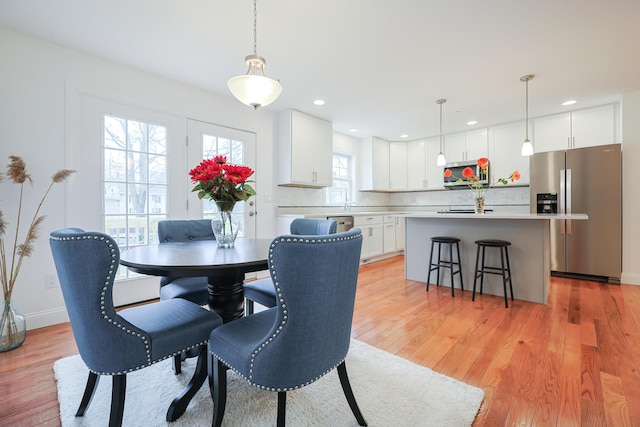 dining area with light wood-type flooring, baseboards, and recessed lighting