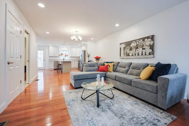 living area with a notable chandelier, light wood-type flooring, visible vents, and recessed lighting