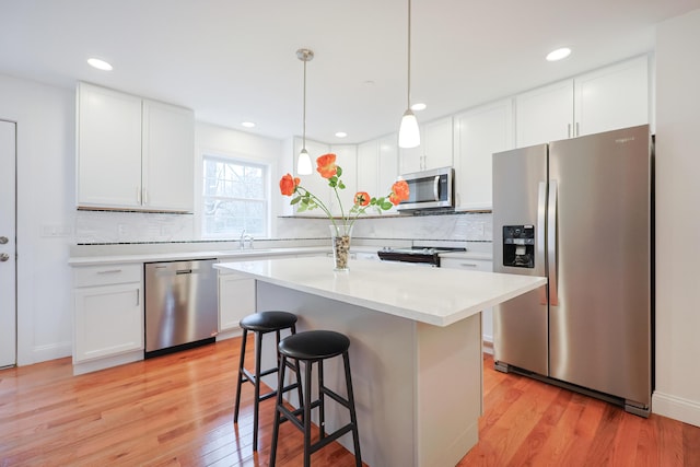 kitchen featuring light wood-style flooring, a breakfast bar, a sink, light countertops, and appliances with stainless steel finishes