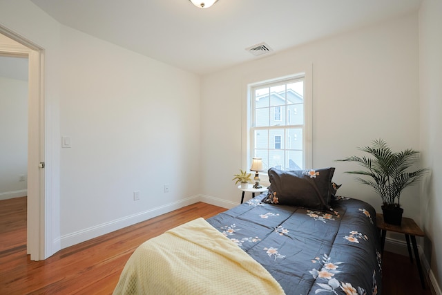 bedroom featuring baseboards, visible vents, and wood finished floors