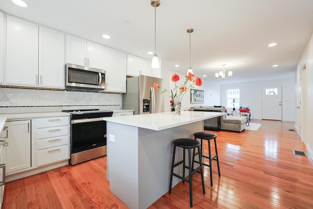 kitchen with visible vents, decorative backsplash, appliances with stainless steel finishes, a breakfast bar, and a center island