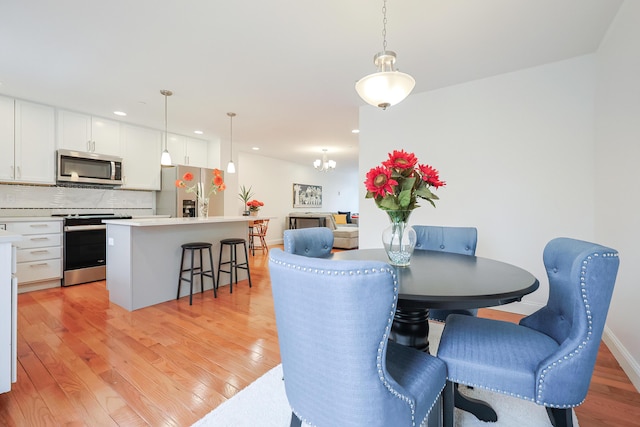 dining area with light wood finished floors, baseboards, a chandelier, and recessed lighting