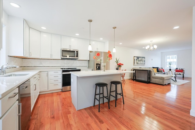 kitchen featuring stainless steel appliances, a breakfast bar, light wood-style floors, and a sink