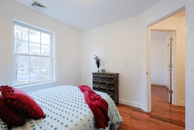 bedroom featuring visible vents, baseboards, and wood finished floors