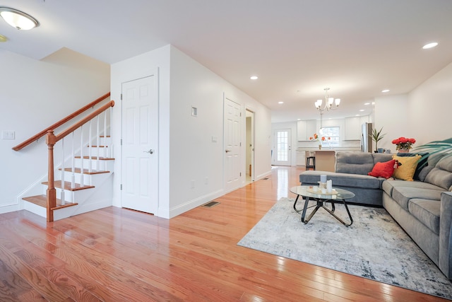 living area featuring visible vents, stairs, light wood-type flooring, a notable chandelier, and recessed lighting