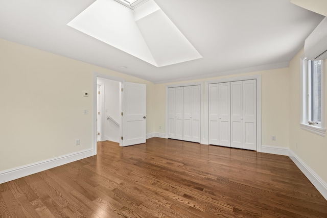 507 S Orleans Rd, Orleans, MA 02653 - unfurnished bedroom with a skylight, two closets, dark wood-style flooring, a wall mounted air conditioner, and baseboards