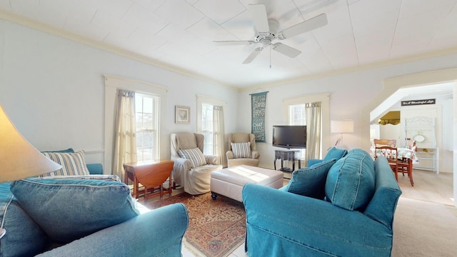 carpeted living room with crown molding and ceiling fan