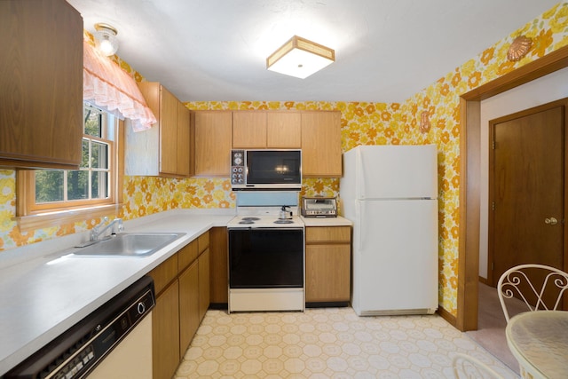 kitchen with white appliances, wallpapered walls, a sink, light countertops, and baseboards