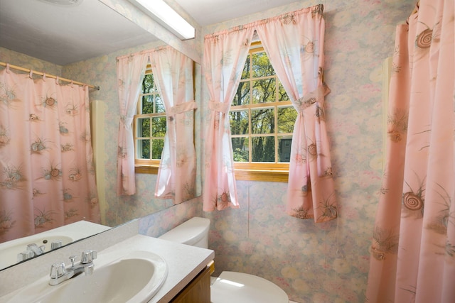 full bathroom with wallpapered walls, healthy amount of natural light, toilet, vanity, and a shower with curtain