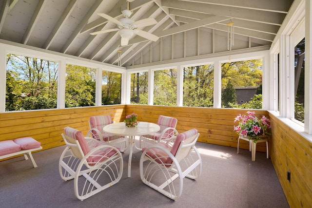 sunroom with ceiling fan, wooden walls, carpet, and outdoor dining space