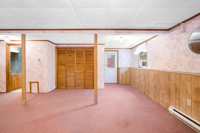 basement featuring baseboard heating, wainscoting, carpet, wallpapered walls, and wood walls