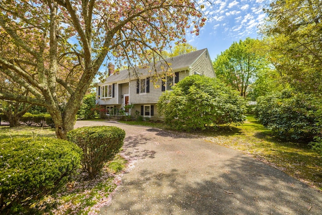 bi-level home with a chimney and driveway