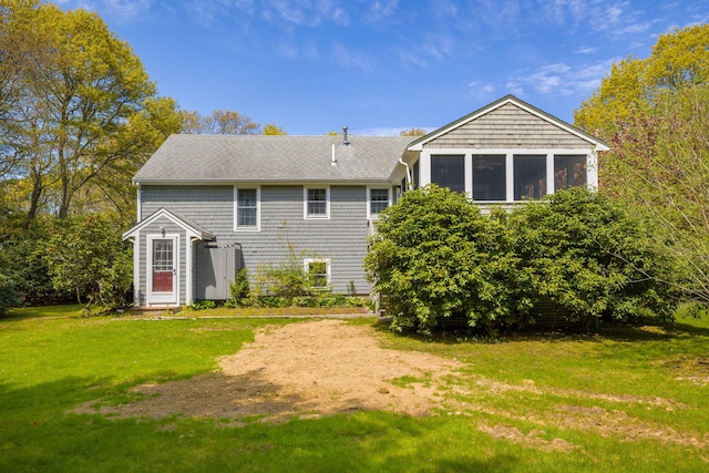 back of house with a yard, roof with shingles, and a sunroom