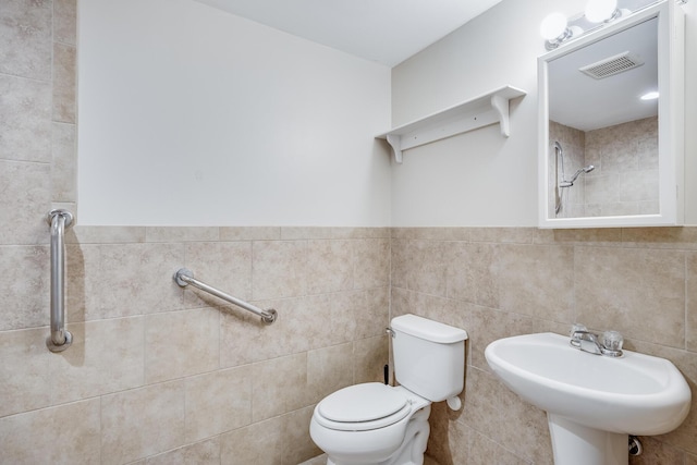 full bath with tiled shower, visible vents, toilet, a sink, and tile walls