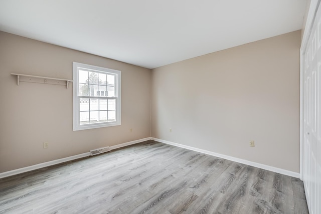 unfurnished bedroom with visible vents, baseboards, a closet, and wood finished floors