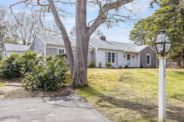 ranch-style home with a chimney and a front lawn
