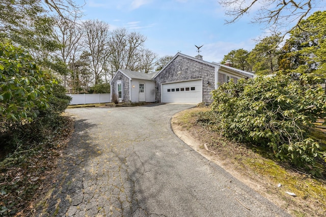 view of home's exterior featuring fence, a garage, and driveway