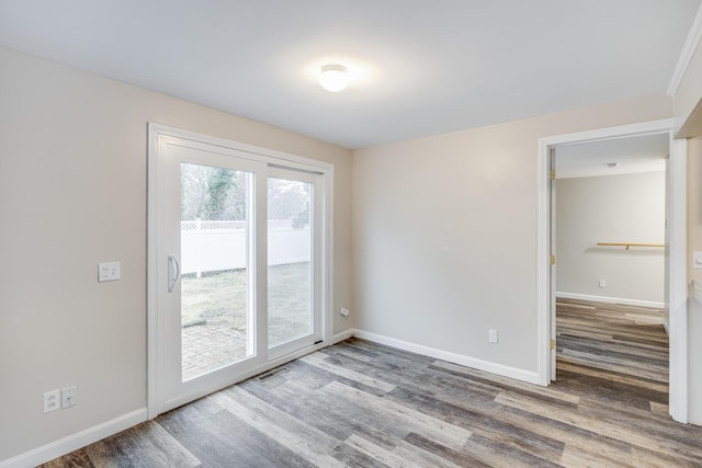 empty room with wood finished floors, baseboards, and visible vents
