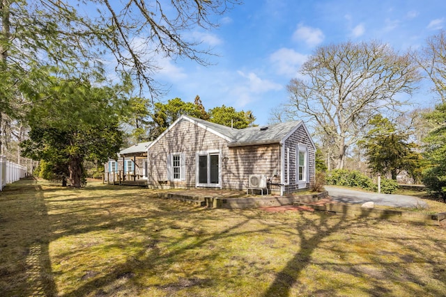 back of property with a deck, fence, and a lawn