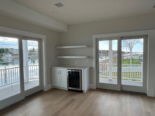 bar with plenty of natural light, a water view, and wine cooler