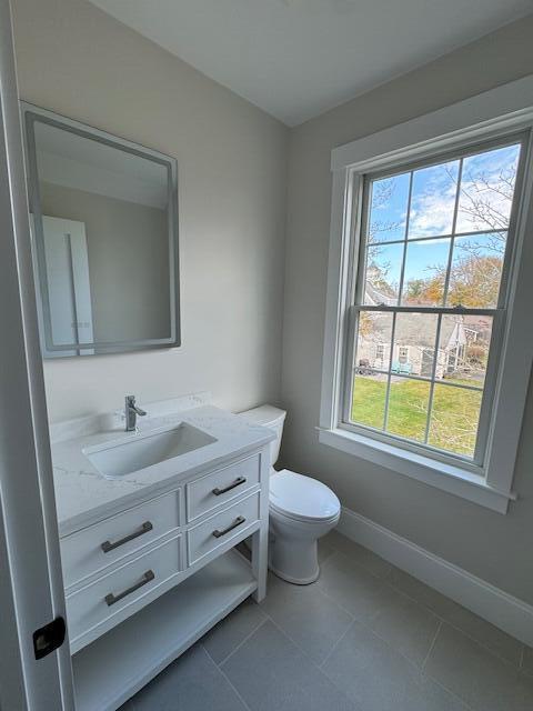 bathroom with a healthy amount of sunlight, toilet, tile patterned flooring, and vanity