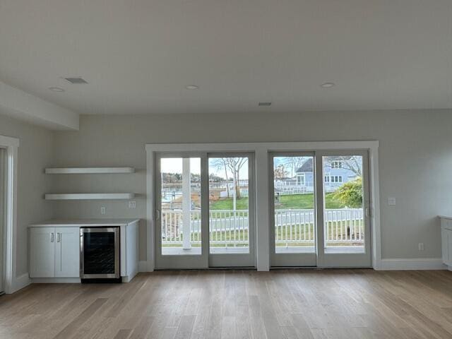 entryway with light hardwood / wood-style flooring and beverage cooler